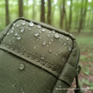 A detailed view of the 1000D nylon material of a tactical phone pouch with water droplets on the surface.
